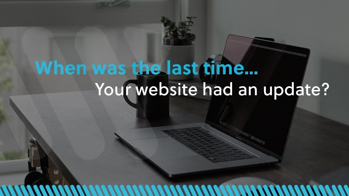 graphic with the words "When was the last time your website had an update" in front of desaturated image of laptop on desk with Woland Web logo