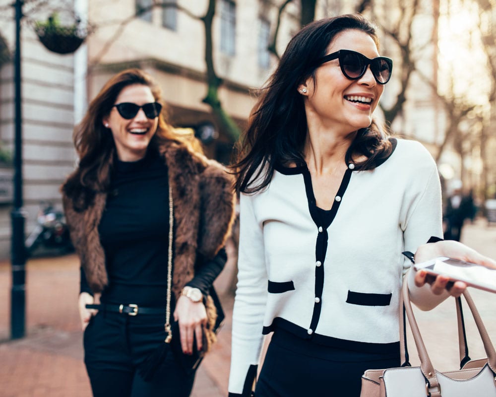 2 fashionable women with sunglasses walking through a city