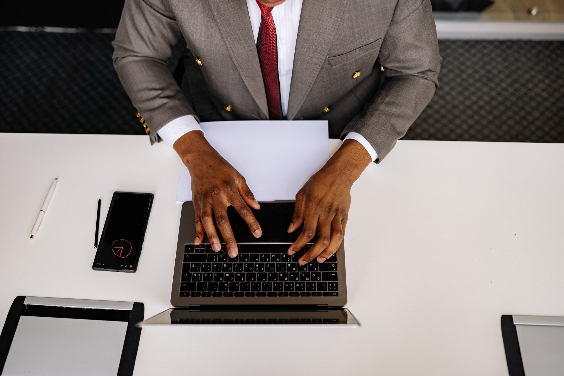 Man in a gray suit typing on a laptop