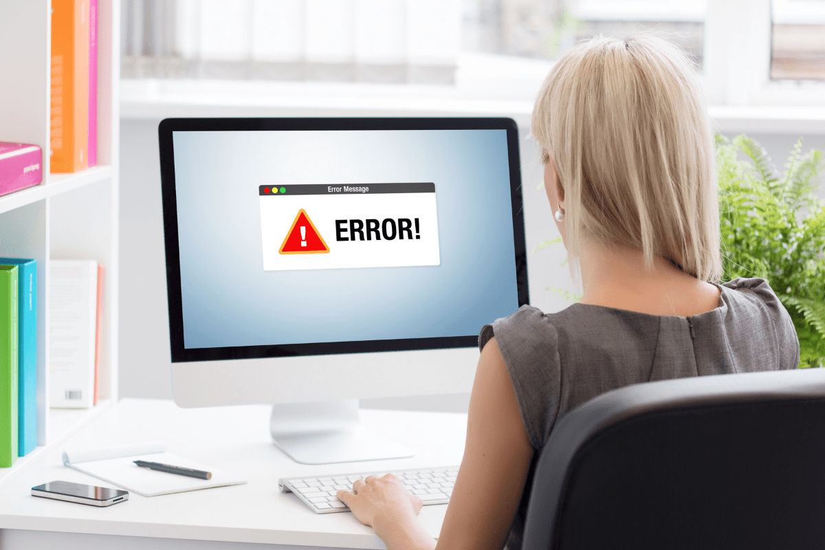 Blonde woman looking at computer monitor with large error message