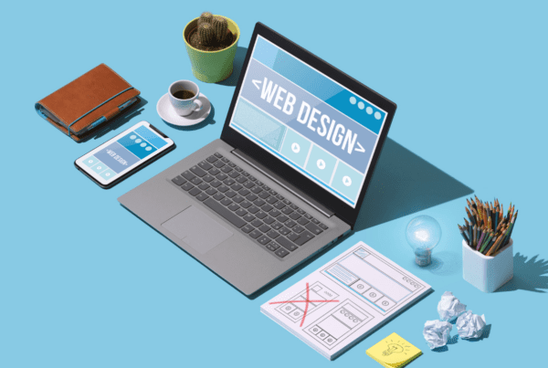 illustration of laptop with the words web design on a blue table with laptop and office supplies