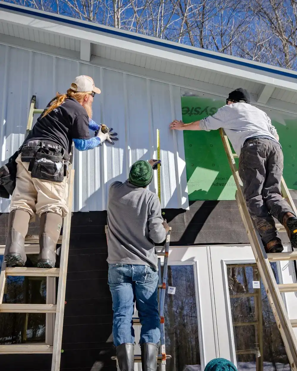 3 men installing siding on a house